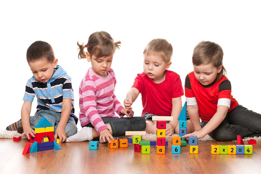  Four children play with colorful wooden blocks on the floor.